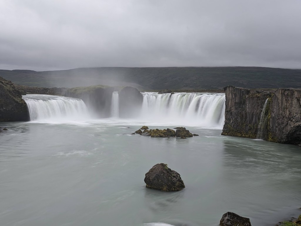 Goðafoss is a waterfall in Iceland, approximately 12 meters (39 feet) tall, but 30 meters (about 98 feet) wide. There are 3 distinct larger plunges and one smaller waterfall to the right.