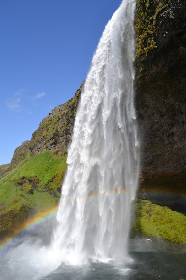Seljalandsfoss is a 200 foot / 61 meter tall waterfall. The plunge waterfall can be explored and you can walk behind it. In this photo, the sun was out, and created a rainbow in front of the falls.