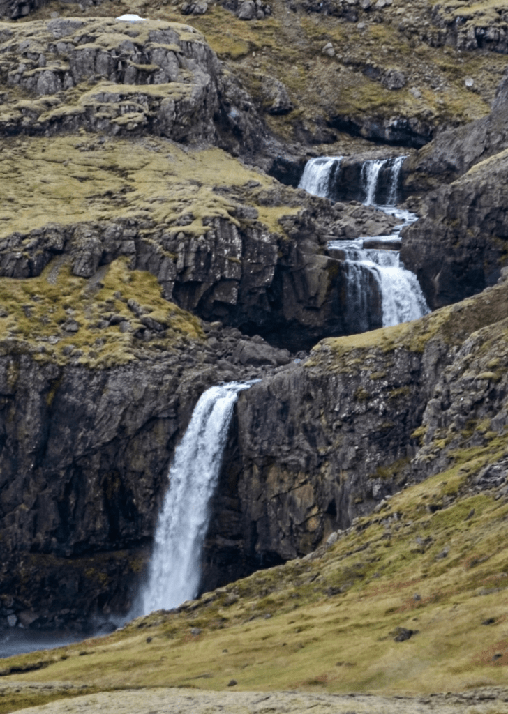 Hænubrekkufoss is a 175 foot / 53 meter tall waterfall in Iceland that drops in three visible portions. Nearly all the rock in Iceland is volcanic in origin.
