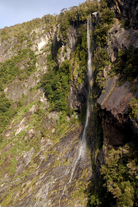 This is one of the many unnamed waterfalls in Milford Sound, New Zealand. They are likely 200-300 feet or 60-90 meters tall.