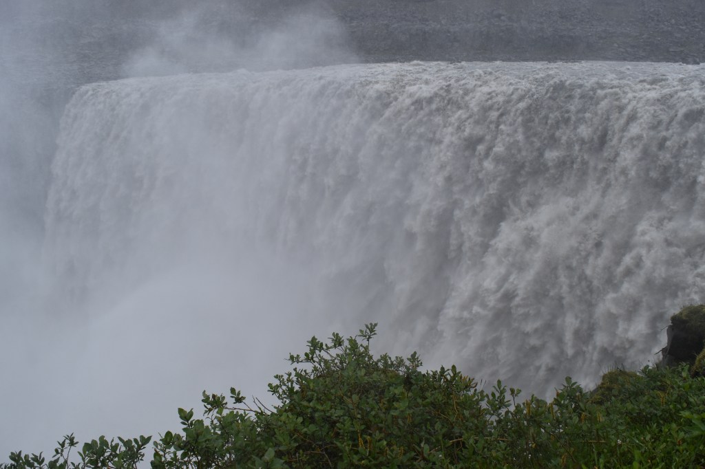 Dettifoss is a massive waterfall in northern Iceland. The waterfall is 144 feet / 44 meters tall but an even more impressive 330 ft / 100 meters wide and there is an amazing amount of waterfall flowing over the waterfall in August 2024.