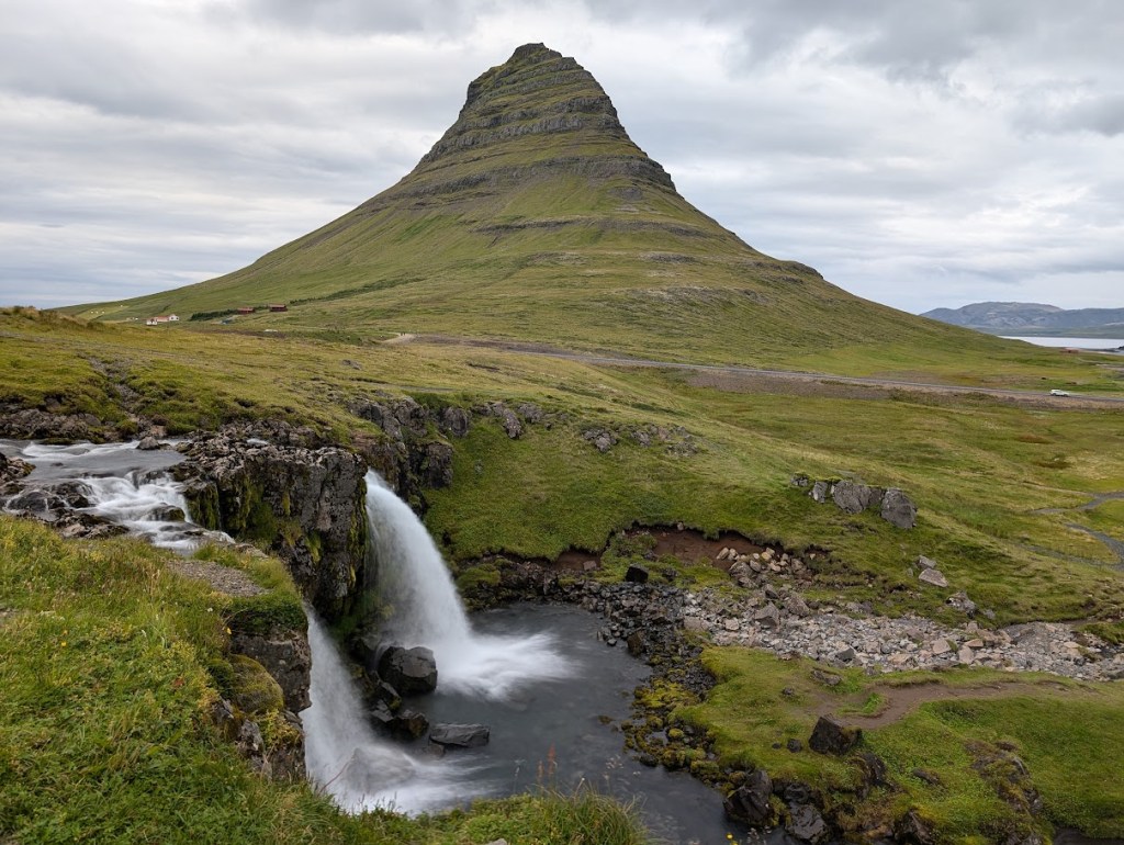 This is the waterfall Kirkjufellsfoss with the mountain Kirkjufell. The mountain is along the seashore and rises 1500 feet (463 meters) from sea level.