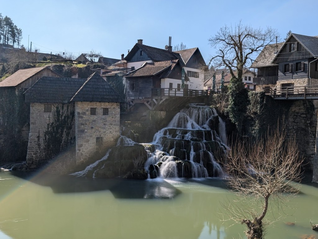 This is a waterfall in Rastoke/Slunj. There are many buildings surrounding the waterfall along with some bridges.