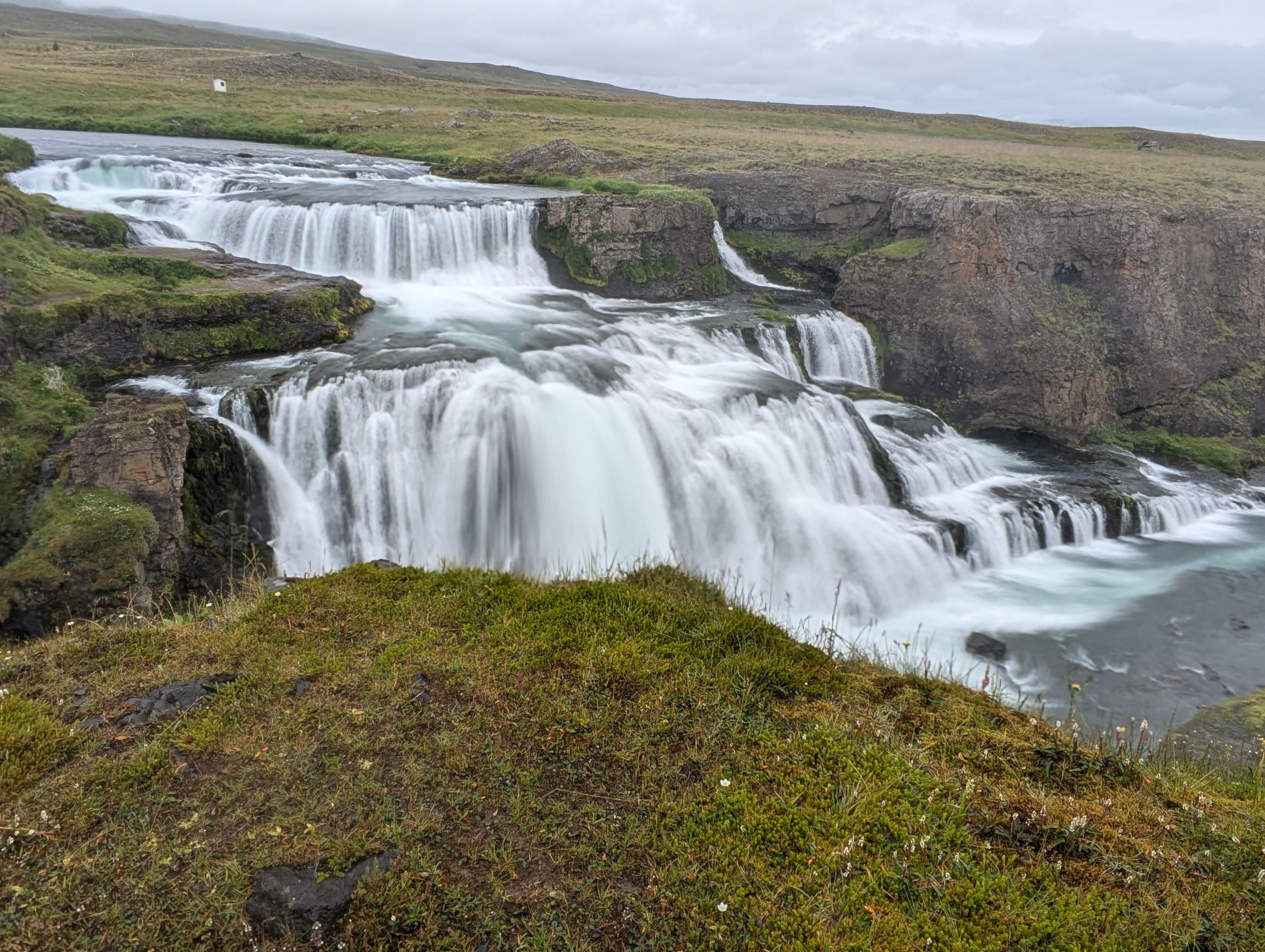 Reykjafoss is a waterfall in Iceland. It is 66 feet / 20 meters tall, and has two main drops. It is an extremely wide waterfall, much wider than it is tall.
